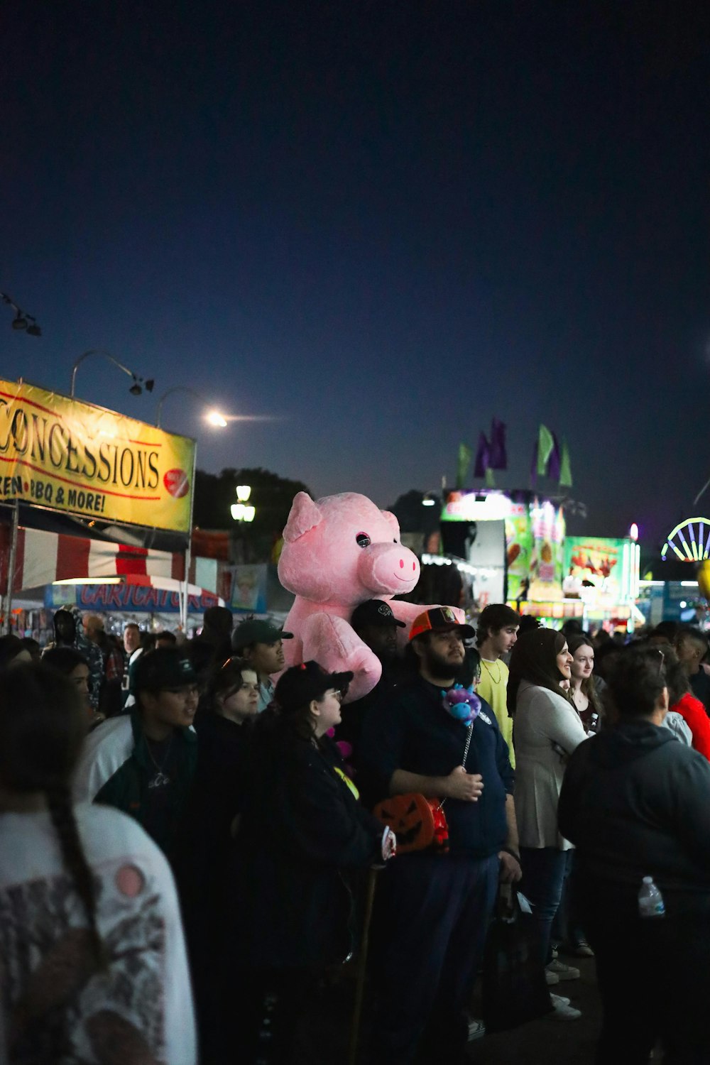 Una multitud de personas de pie alrededor de un carnaval por la noche