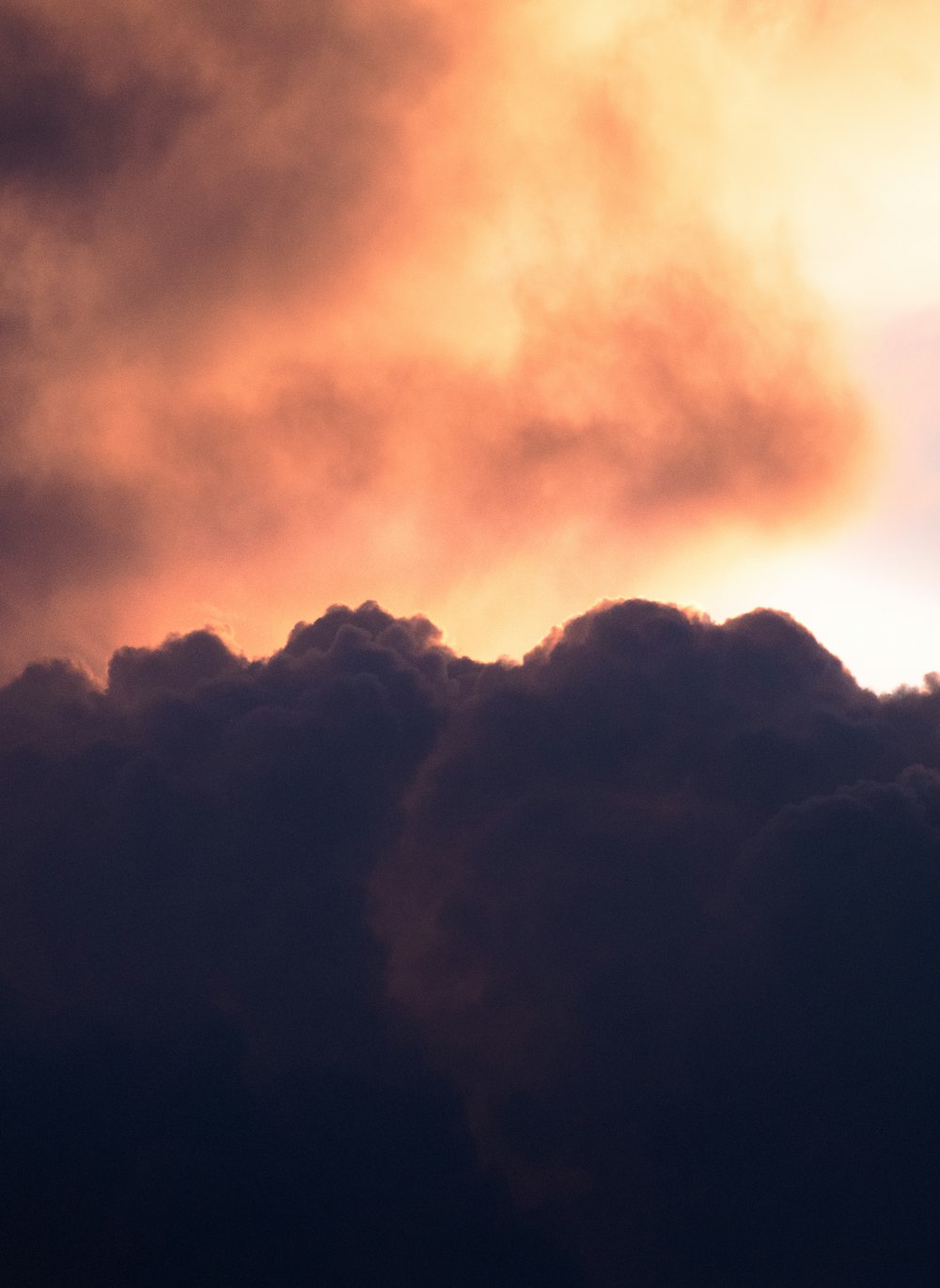 a plane flying through a cloudy sky at sunset