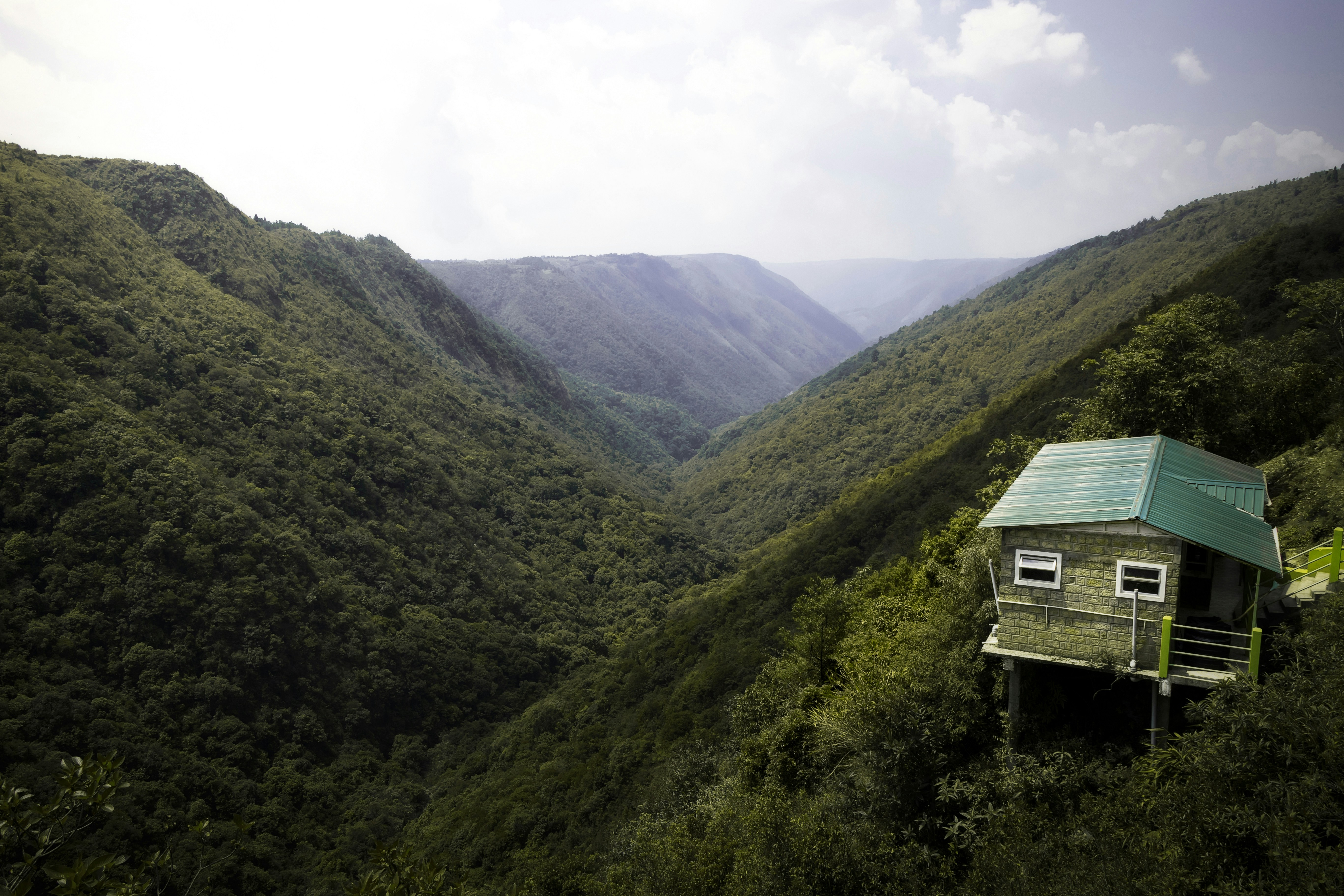 a house in the middle of a lush green valley, Dream house amidst the scenic valley.