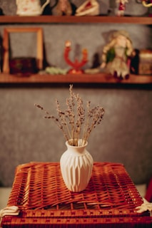 A vintage ceramic vase with delicate floral patterns, paired with dried lavender stems against a soft beige background.