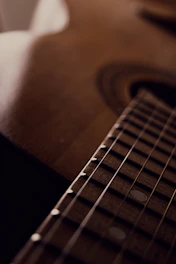 Close-up of a well-used acoustic guitar showing worn frets and a small crack near the bridge.