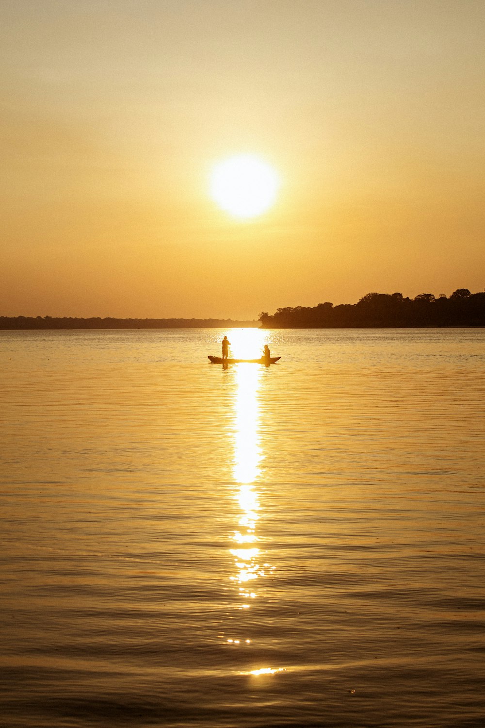 eine Person in einem Boot auf einem See bei Sonnenuntergang