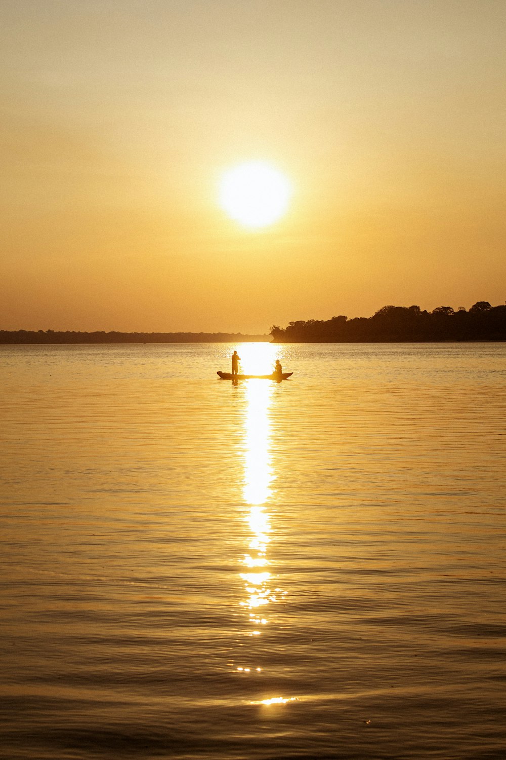 夕暮れ時の湖に浮かぶボートに乗った人