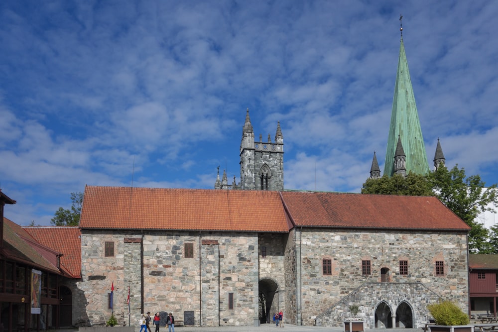 a stone building with a red roof and a green steeple