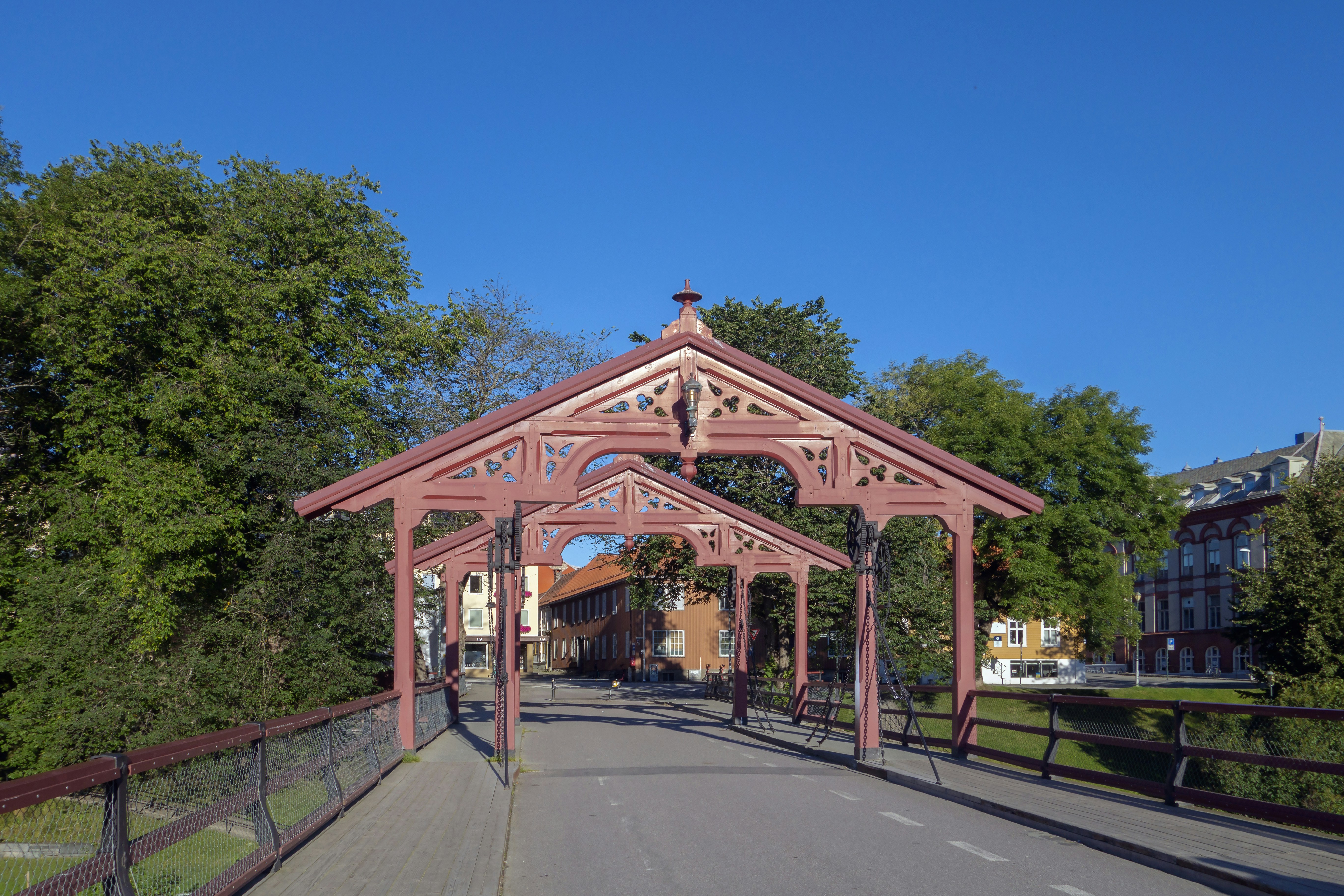 a wooden bridge over a road surrounded by trees