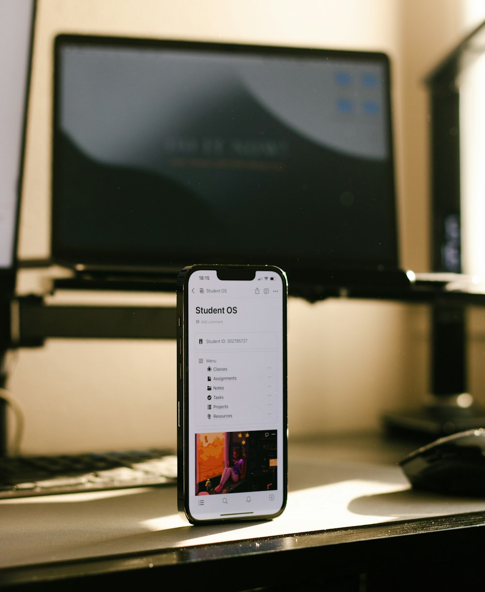 a cell phone sitting on a desk next to a laptop