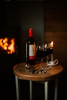 A cozy setting with a bottle of red wine, a filled glass, and elegant wine accessories on a wooden table.