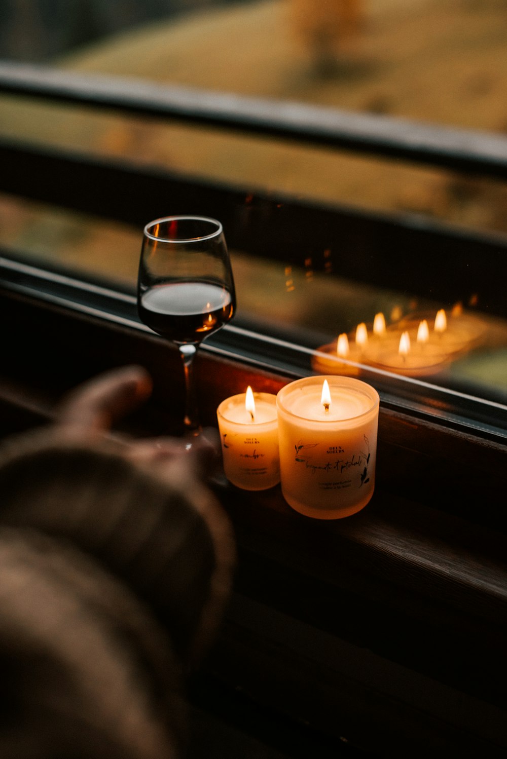 a person holding a glass of wine next to candles