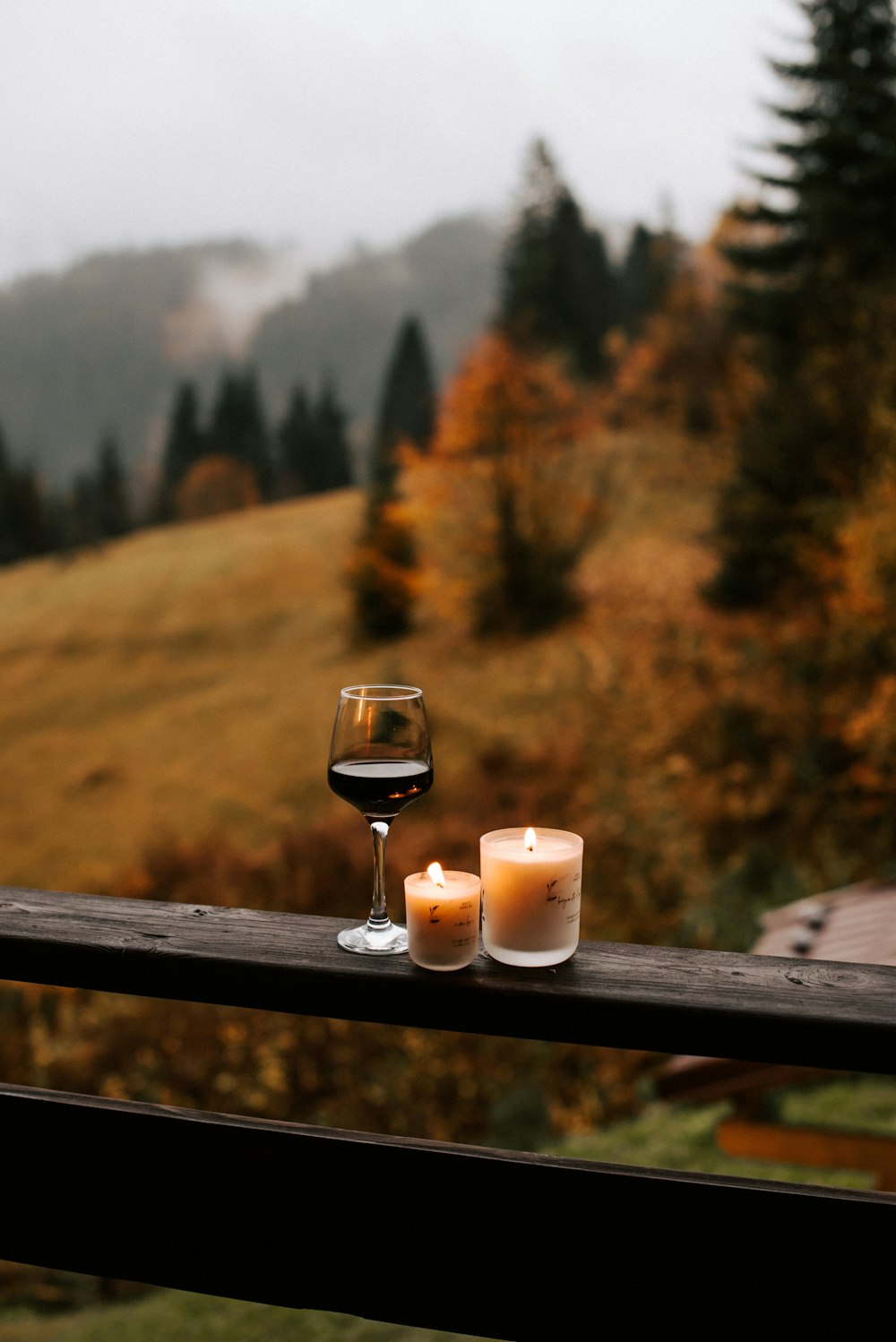 two candles and a glass of wine on a balcony