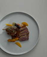 A vibrant dish featuring duck confit served with seasonal vegetables and a rich sauce.