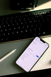 a cell phone sitting on top of a desk next to a keyboard