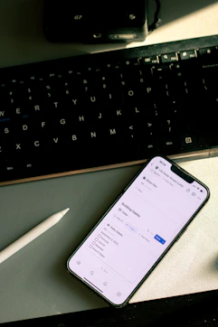 a cell phone sitting on top of a desk next to a keyboard