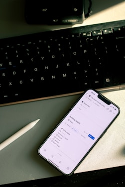 a cell phone sitting on top of a desk next to a keyboard