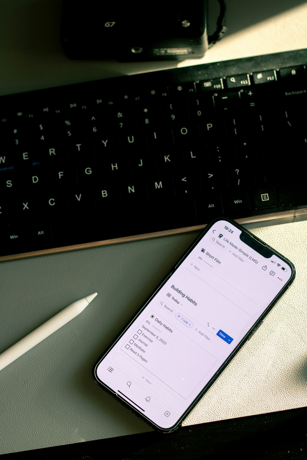 a cell phone sitting on top of a desk next to a keyboard