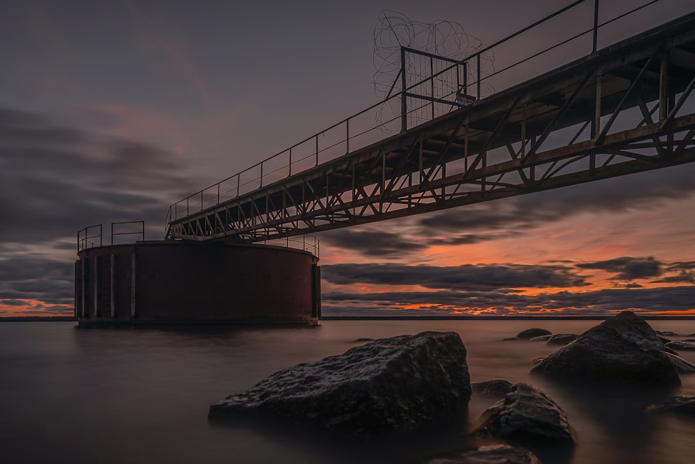 a bridge over a body of water with rocks in the foreground