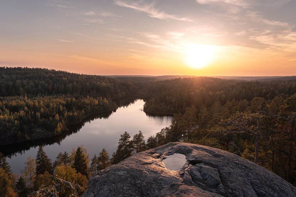 the sun is setting over a lake surrounded by trees