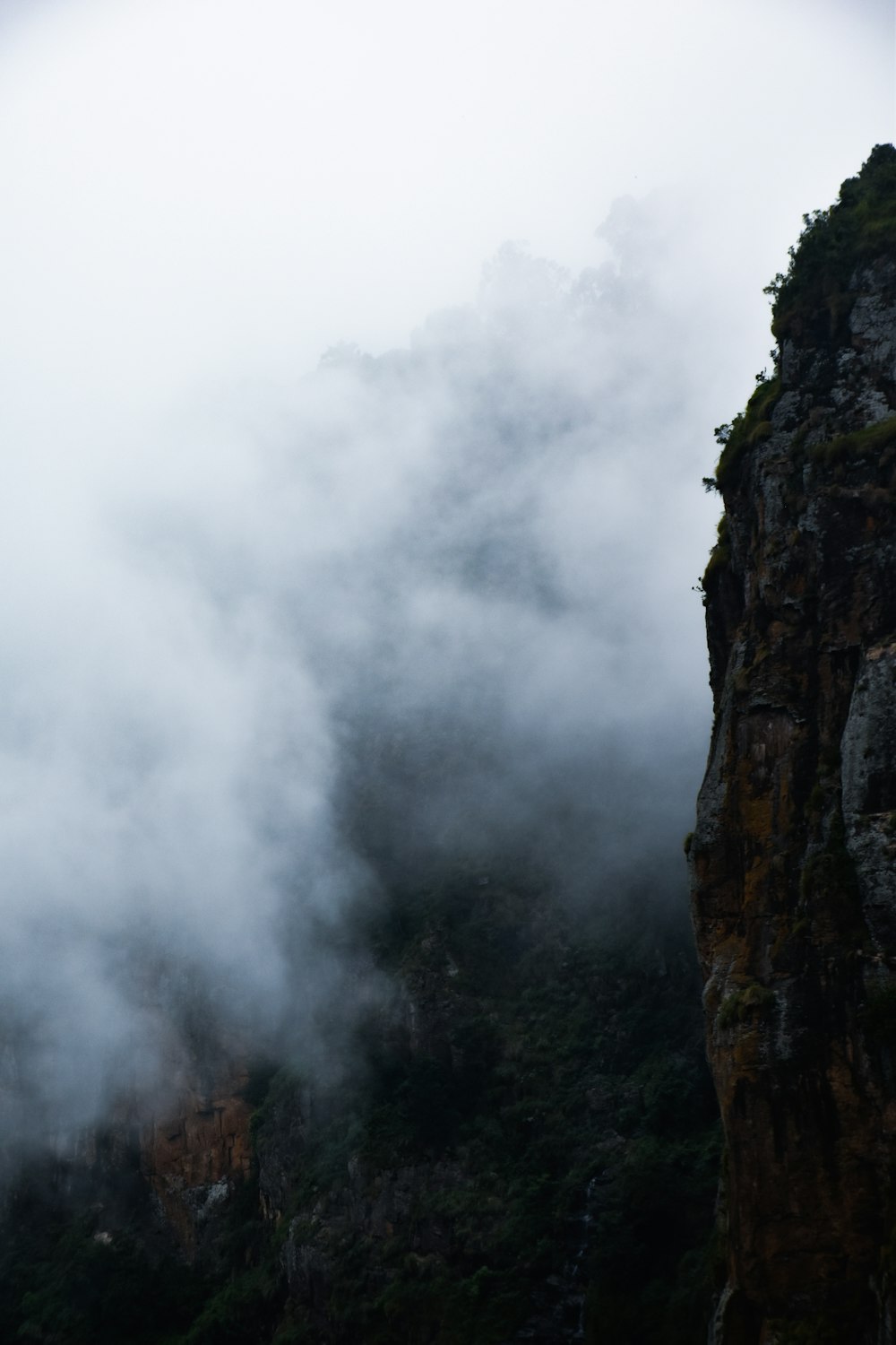 a mountain covered in fog and clouds on a cloudy day