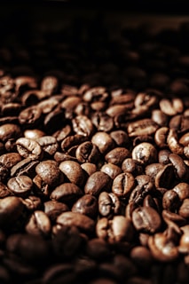 Close-up of rich, roasted coffee beans spilling from a burlap sack with a warm brown background.