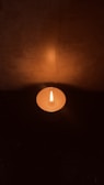 An artistic shot of a lit candle casting warm light in darkness.