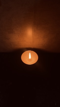 An artistic shot of a lit candle casting warm light in darkness.