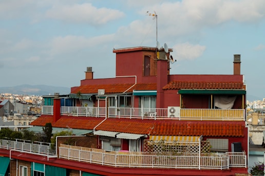 a tall red building with a balcony and a clock tower