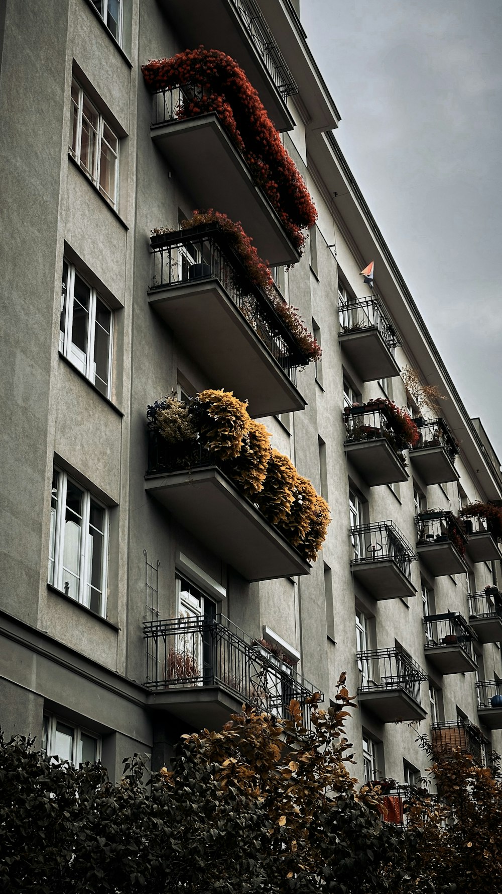 a tall building with balconies and plants growing on the balconies