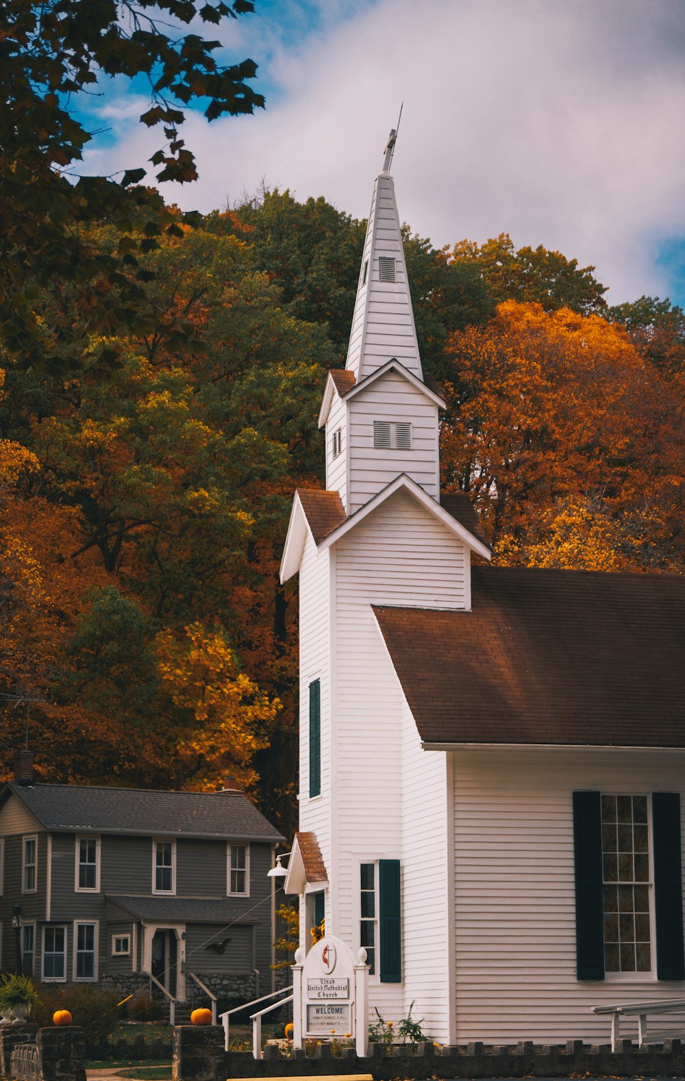 a white church with a steeple surrounded by trees