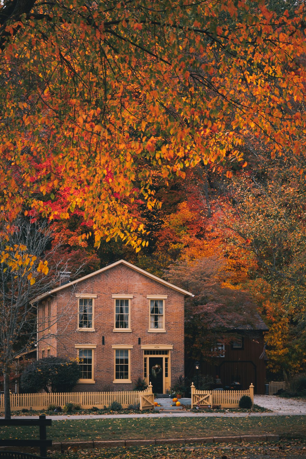 a brick house surrounded by trees in autumn