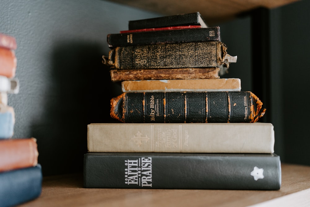 a stack of books sitting on top of a wooden shelf