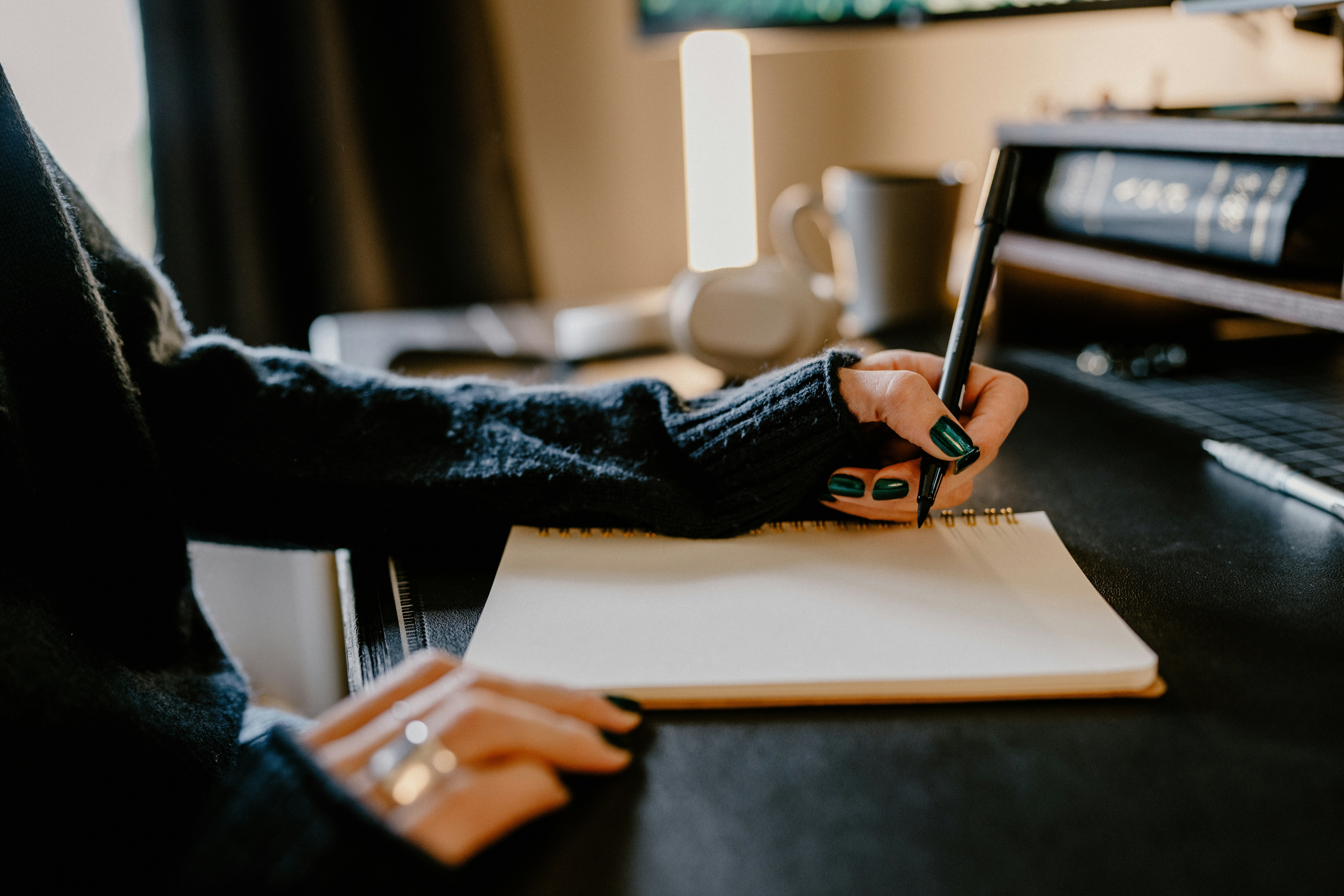 a person holding a pen and writing on a notebook
