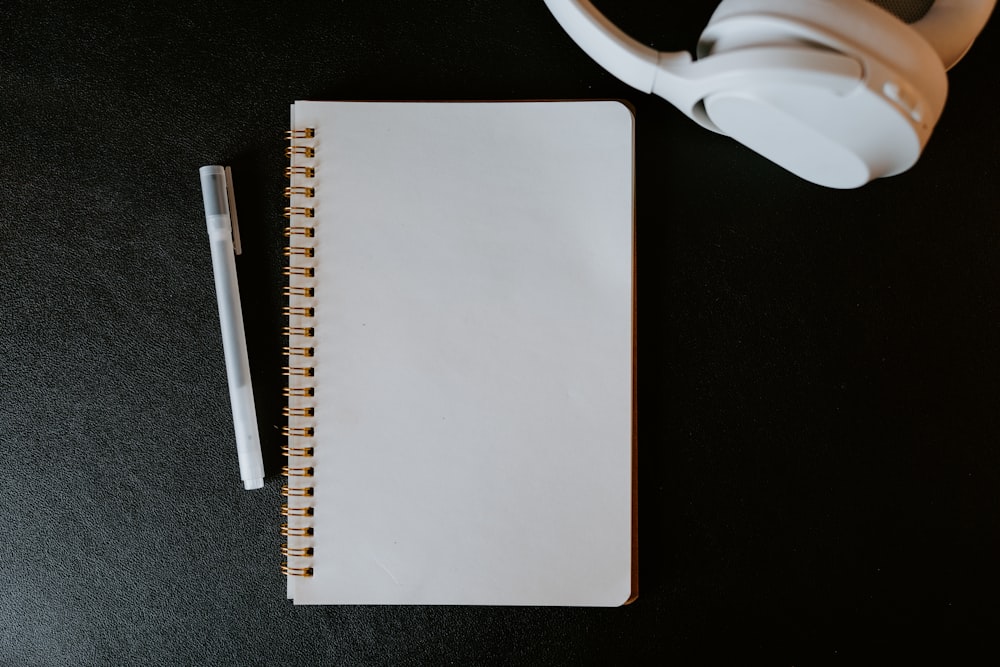 a notebook with a pen and headphones on a table