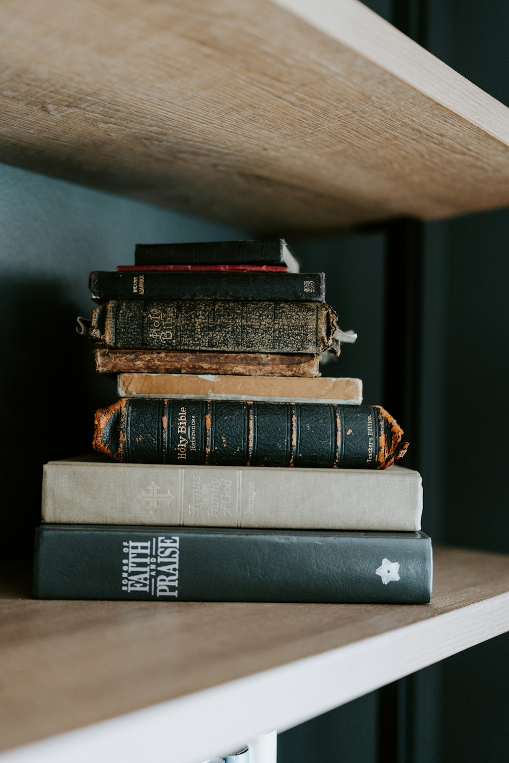 a stack of books sitting on top of a wooden shelf