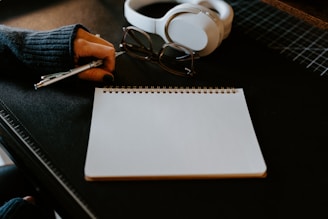 a notepad, pen and headphones on a table