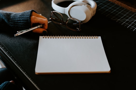 a notepad, pen and headphones on a table