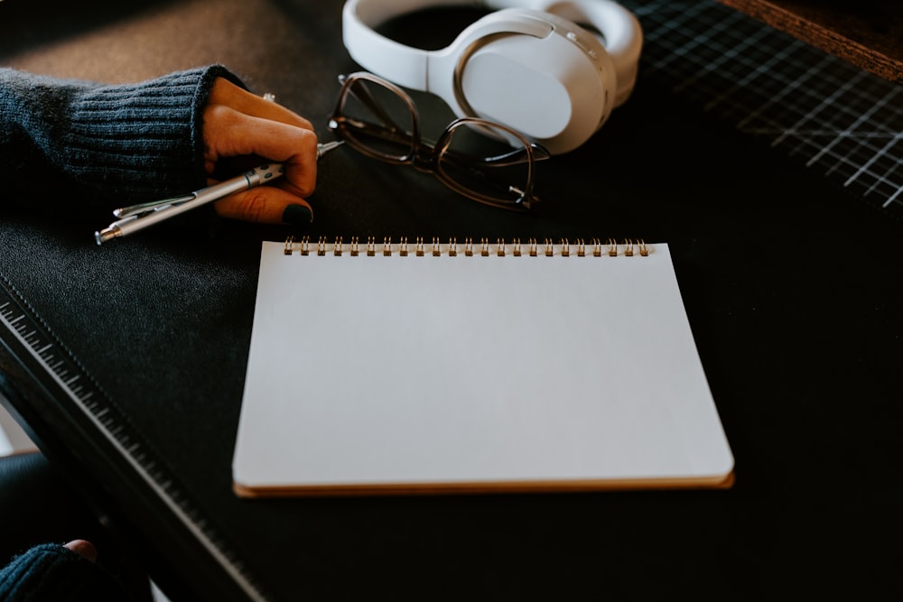 a notepad, pen and headphones on a table