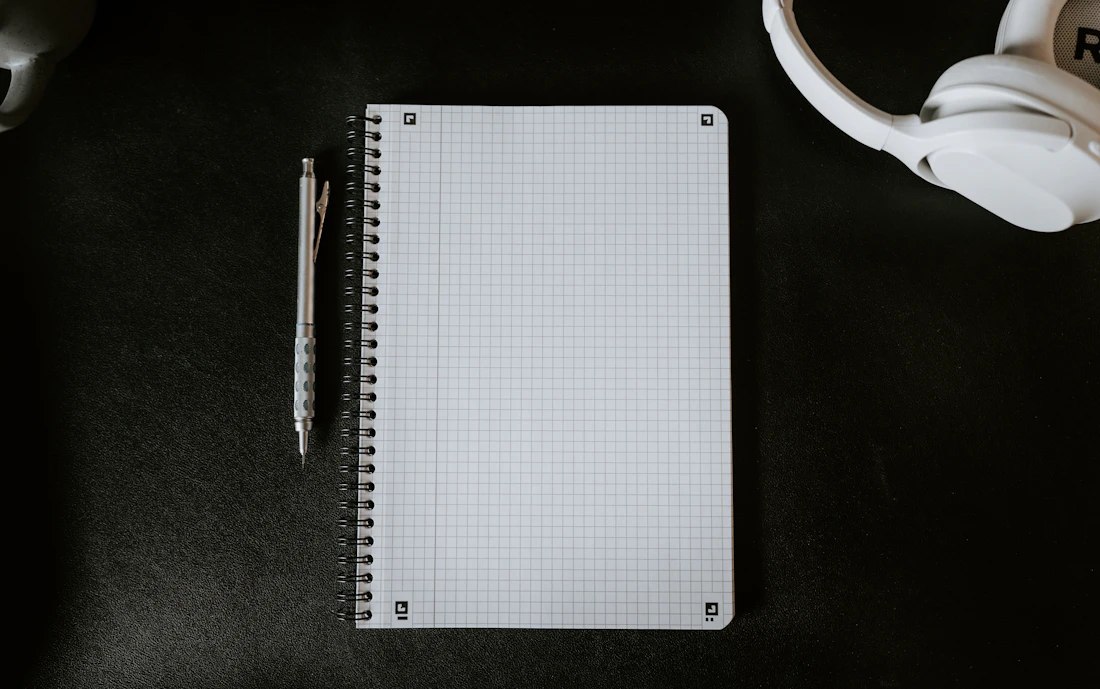 A notepad with a pen next to a mug