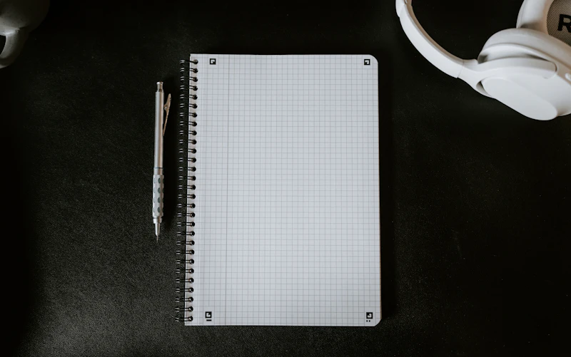 A notepad with a pen next to a mug