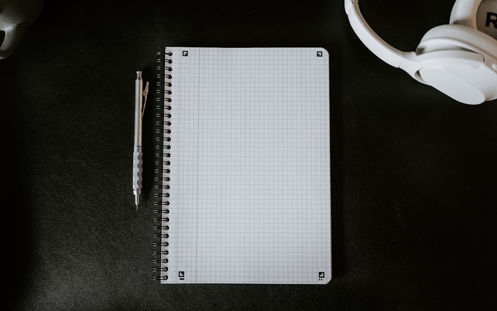 a notepad with a pen on top of it next to a mug