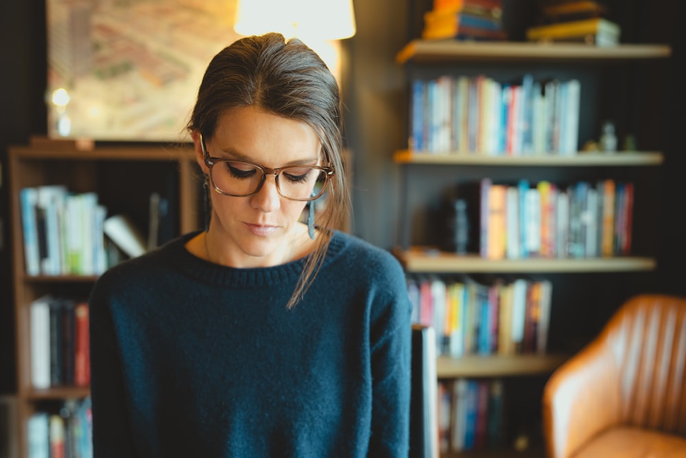 a woman wearing glasses looking at a cell phone