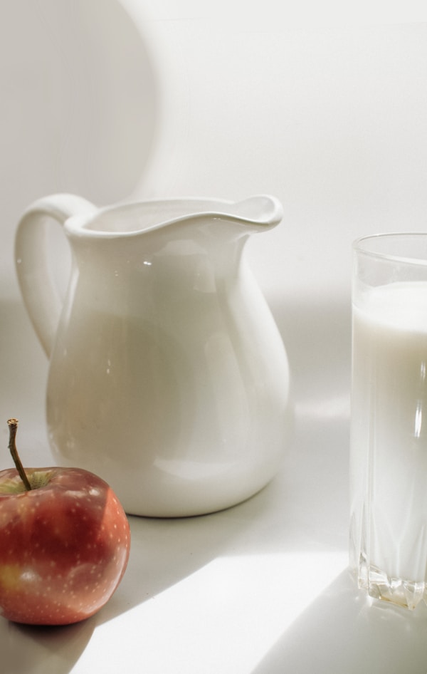 A glass of milk and an apple on a table