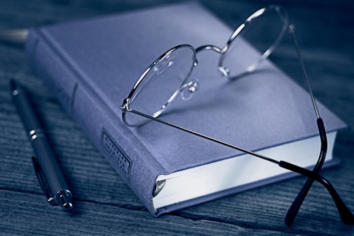 A conference proceedings book displayed alongside a pair of reading glasses and a pen.