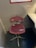 A chair with a red cushioned seat and backrest, labeled with 'TGV' and 'SNCF' logos, is positioned in a small, enclosed space near a desk. The chair has a metal base with a swivel feature. Above the chair, a framed schedule or chart is mounted on the wall.