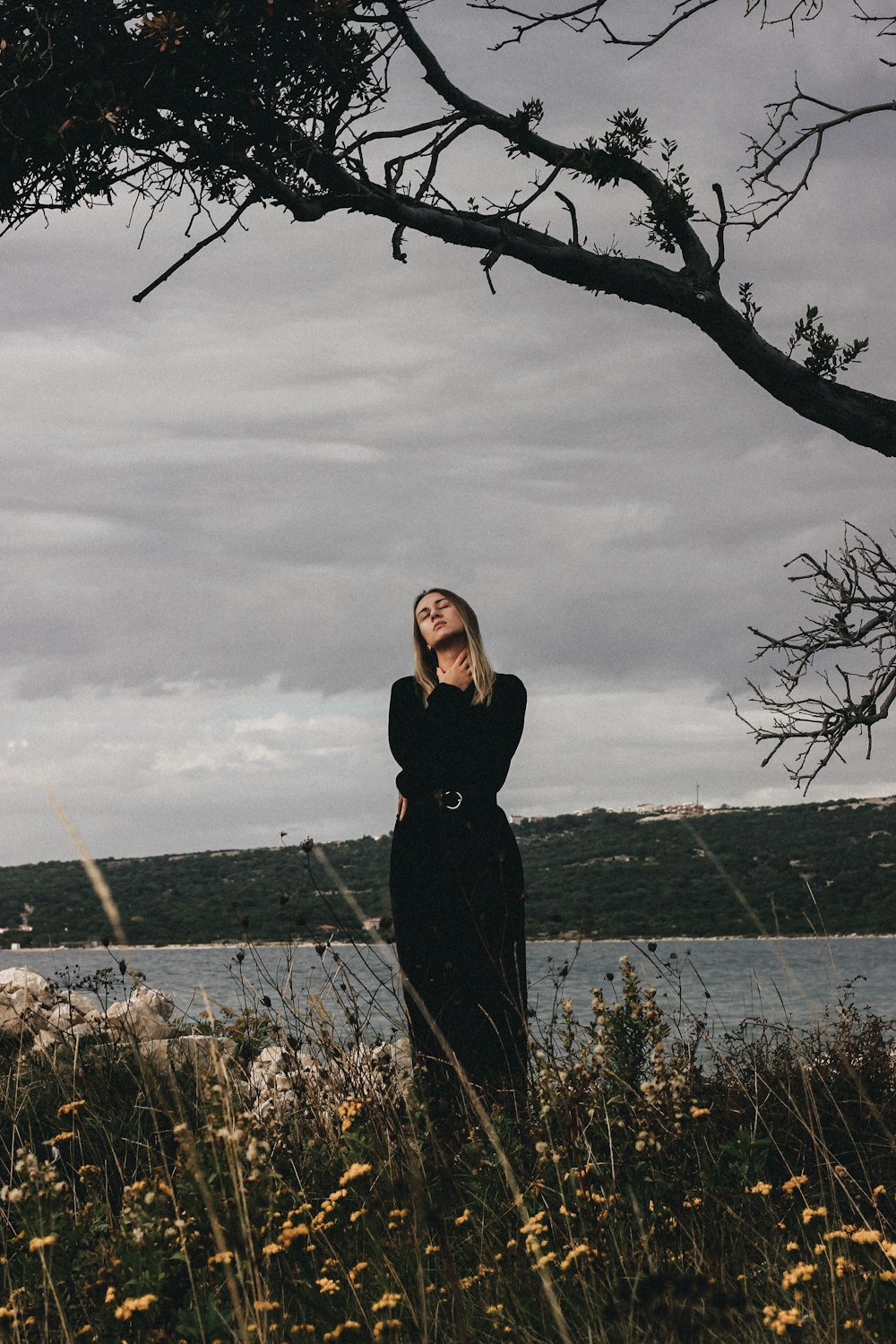 a woman in a black dress standing in a field