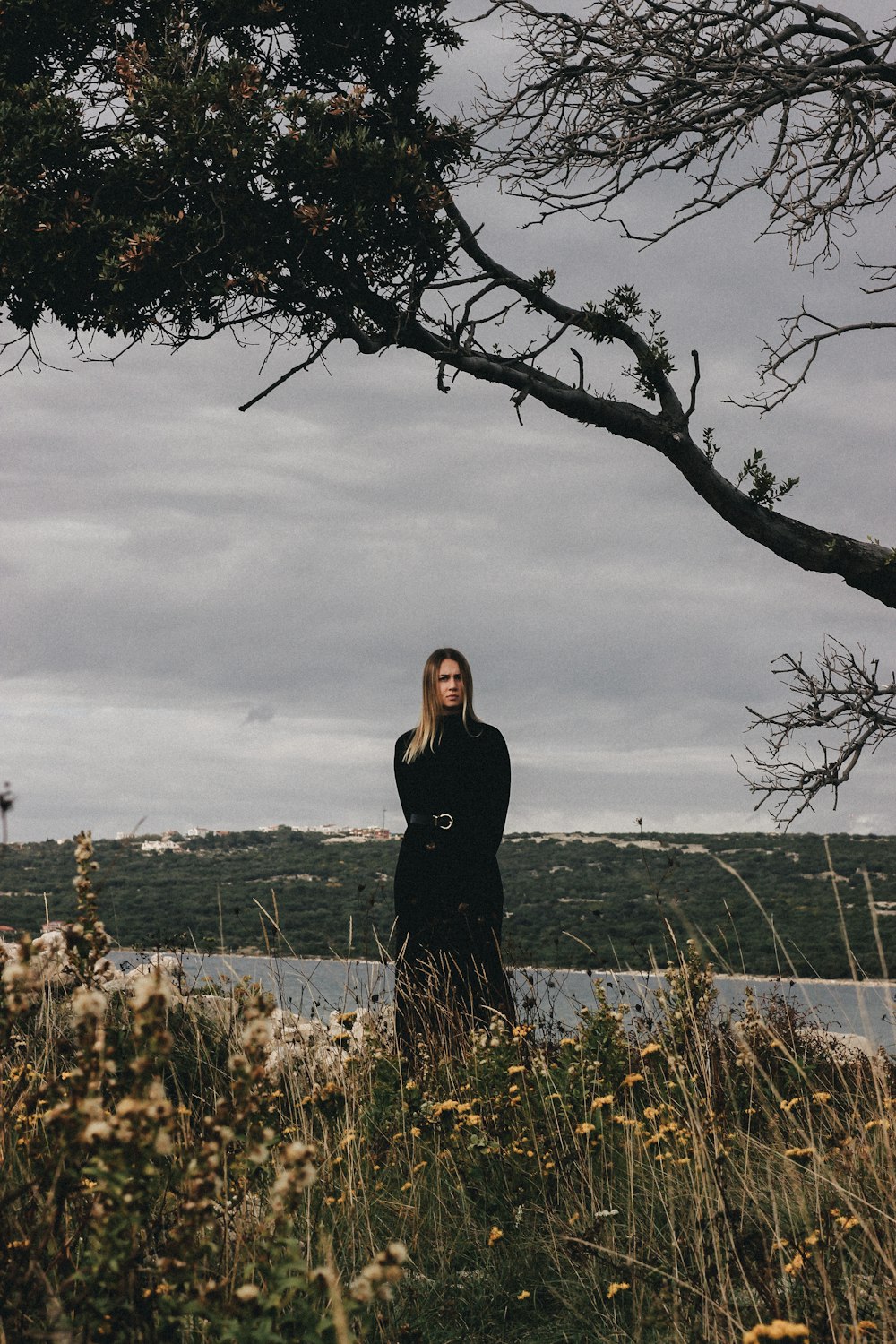 a woman standing in a field next to a tree