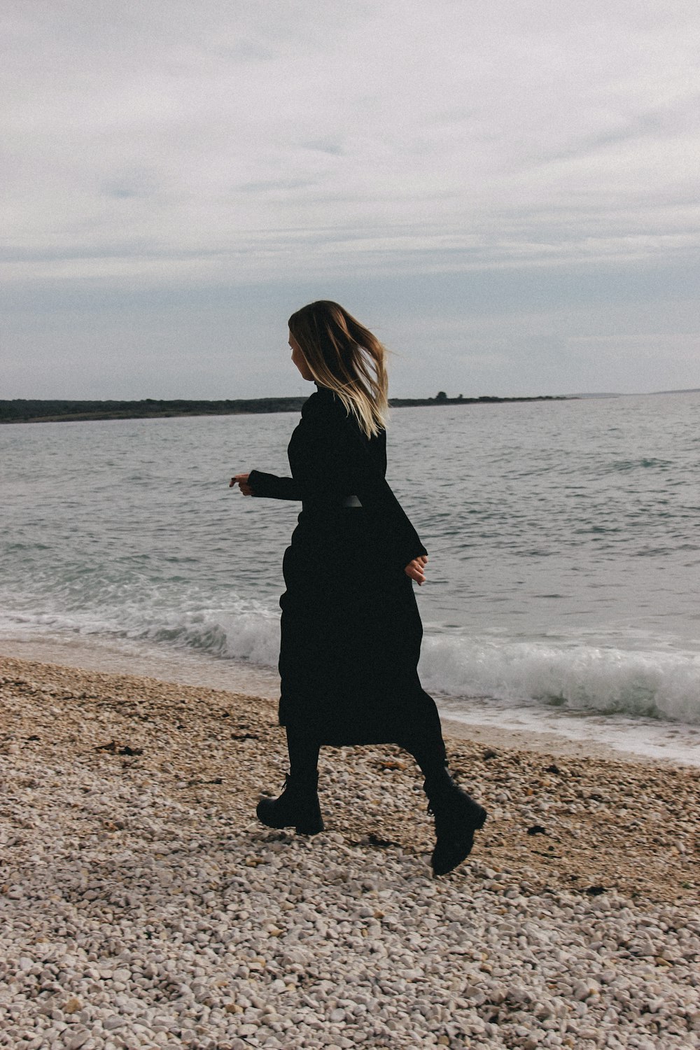 a woman walking on a beach next to the ocean