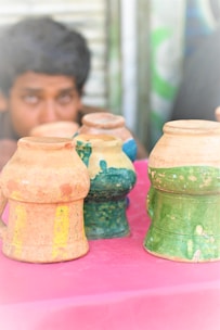 A finished collection of colourful boob pots displayed on a rustic wooden table.