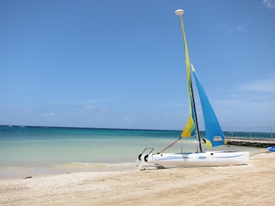 a sailboat on the beach with a blue sky in the background