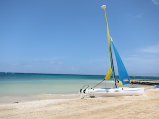 a sailboat on the beach with a blue sky in the background