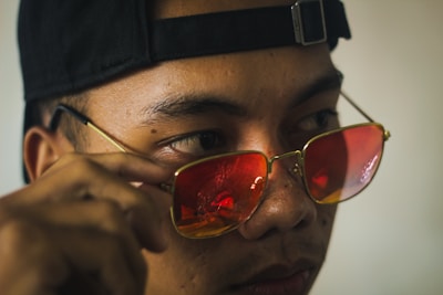 A close-up of a person adjusting their fashionable glasses.