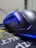 A close-up view of a sleek, black gaming mouse with blue LED lighting accents. The mouse is resting on a mouse pad with Asian characters and yellow and white text. The focus is on the curves and lighting of the mouse, giving it a futuristic and stylish appearance.